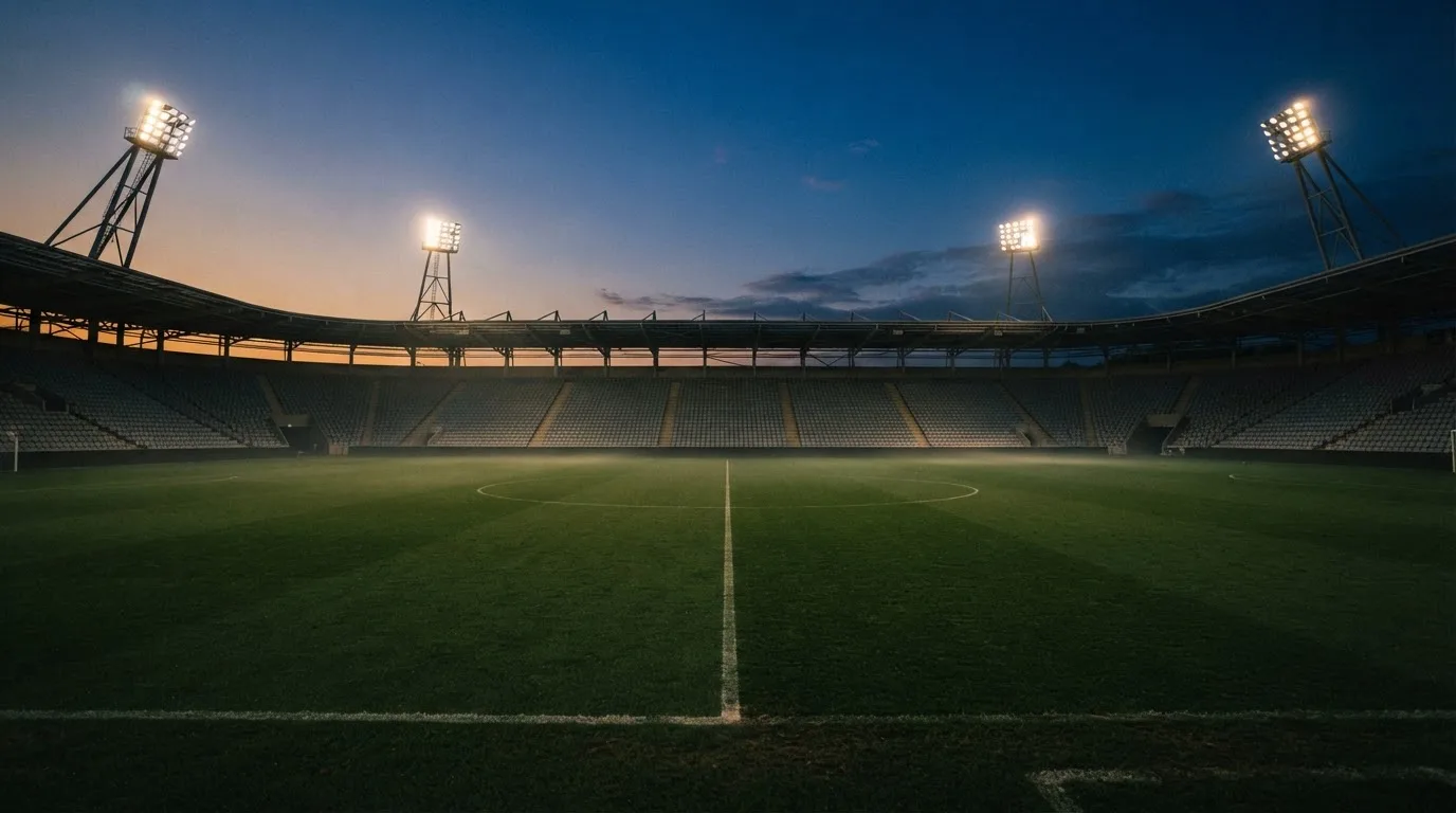 Een leeg voetbalstadion met lichtmasten bij schemering