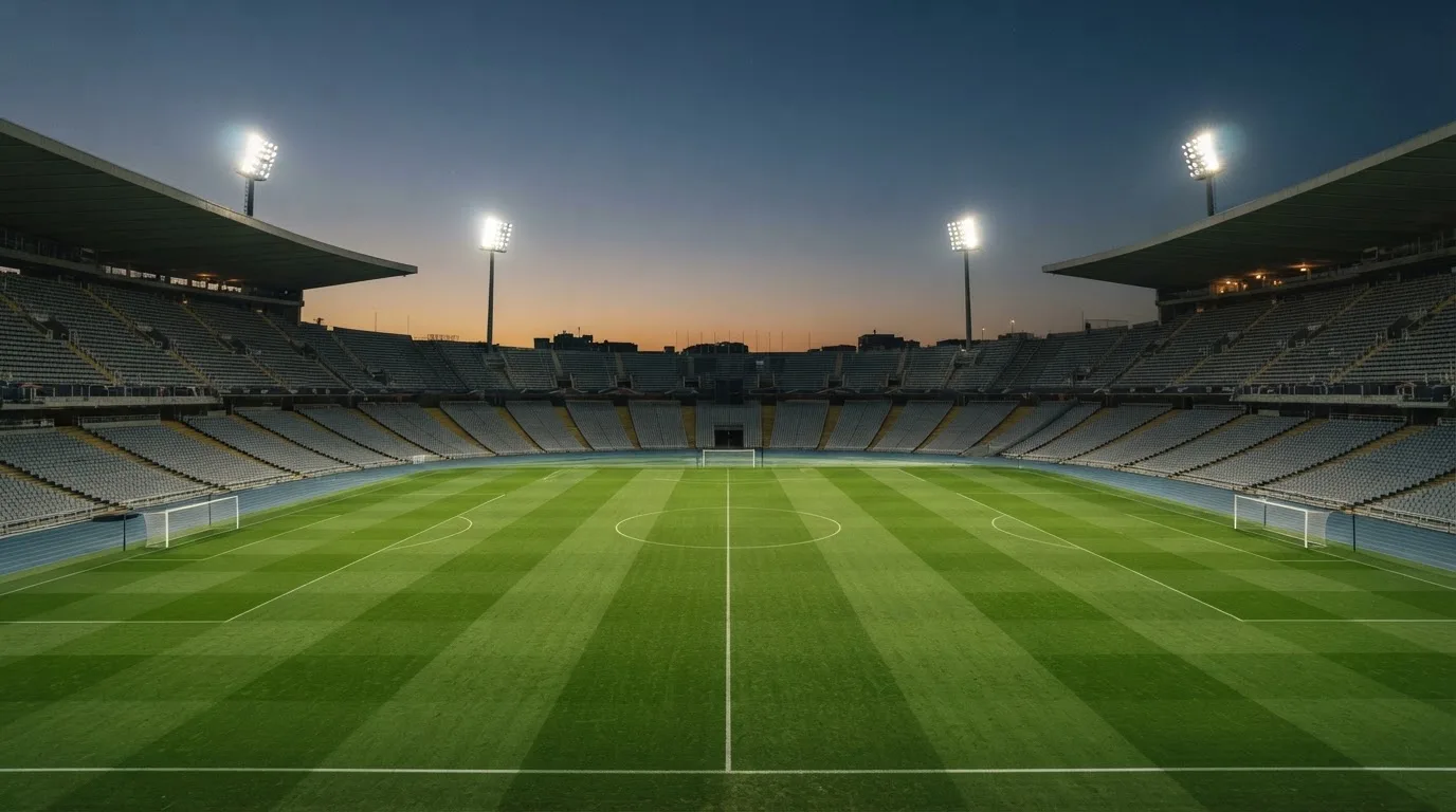 Een leeg voetbalstadion met lichtmasten bij schemering