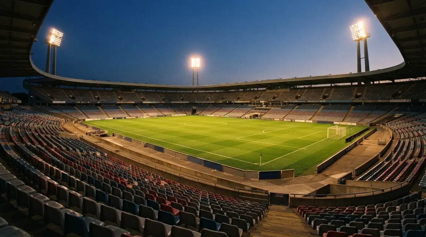 Een leeg voetbalstadion met lichtmasten bij schemering