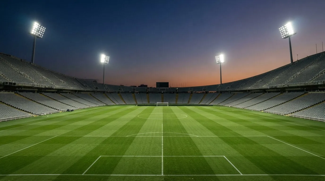 Een leeg voetbalstadion met lichtmasten bij schemering