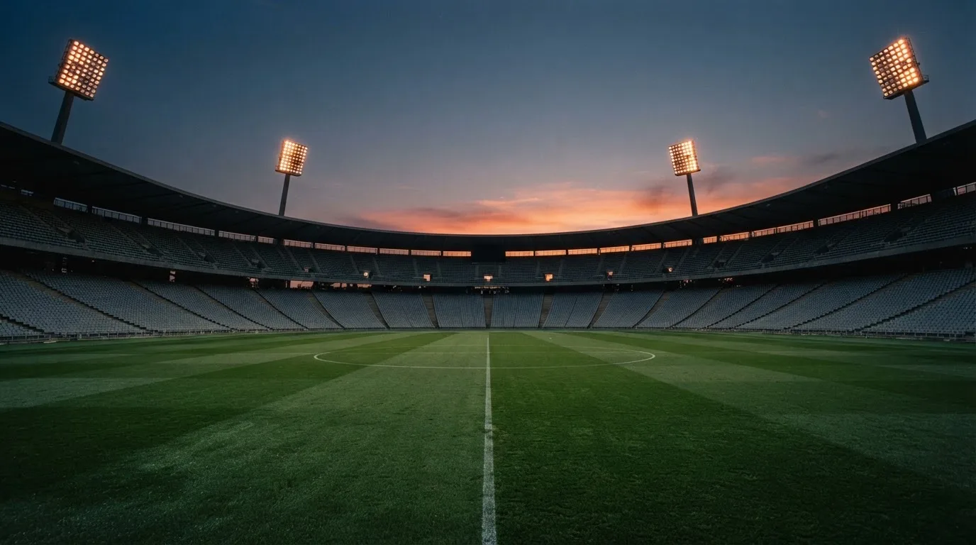 Een leeg voetbalstadion met lichtmasten bij schemering
