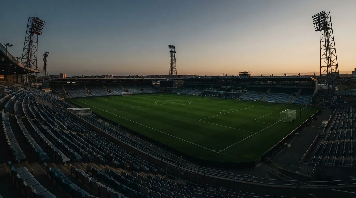 Een leeg voetbalstadion met lichtmasten bij schemering