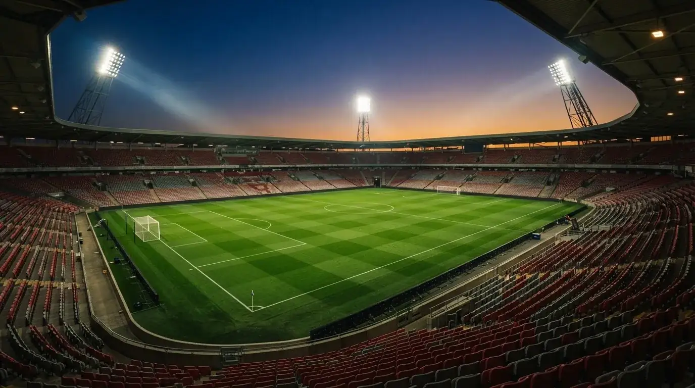 Een leeg voetbalstadion met lichtmasten bij schemering