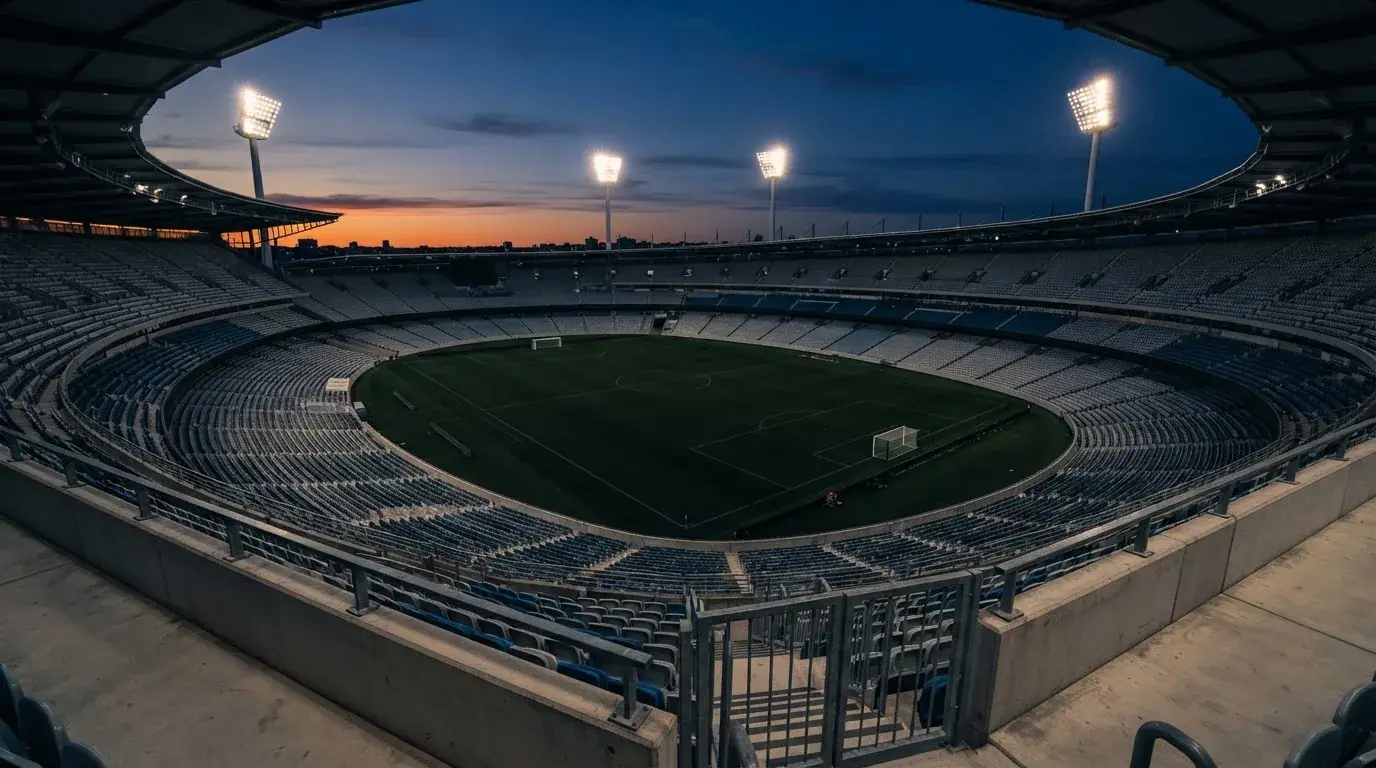 Een leeg voetbalstadion met lichtmasten bij schemering