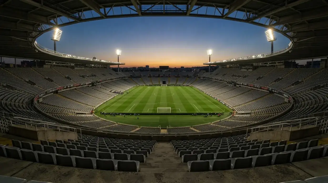 Een leeg voetbalstadion met lichtmasten bij schemering