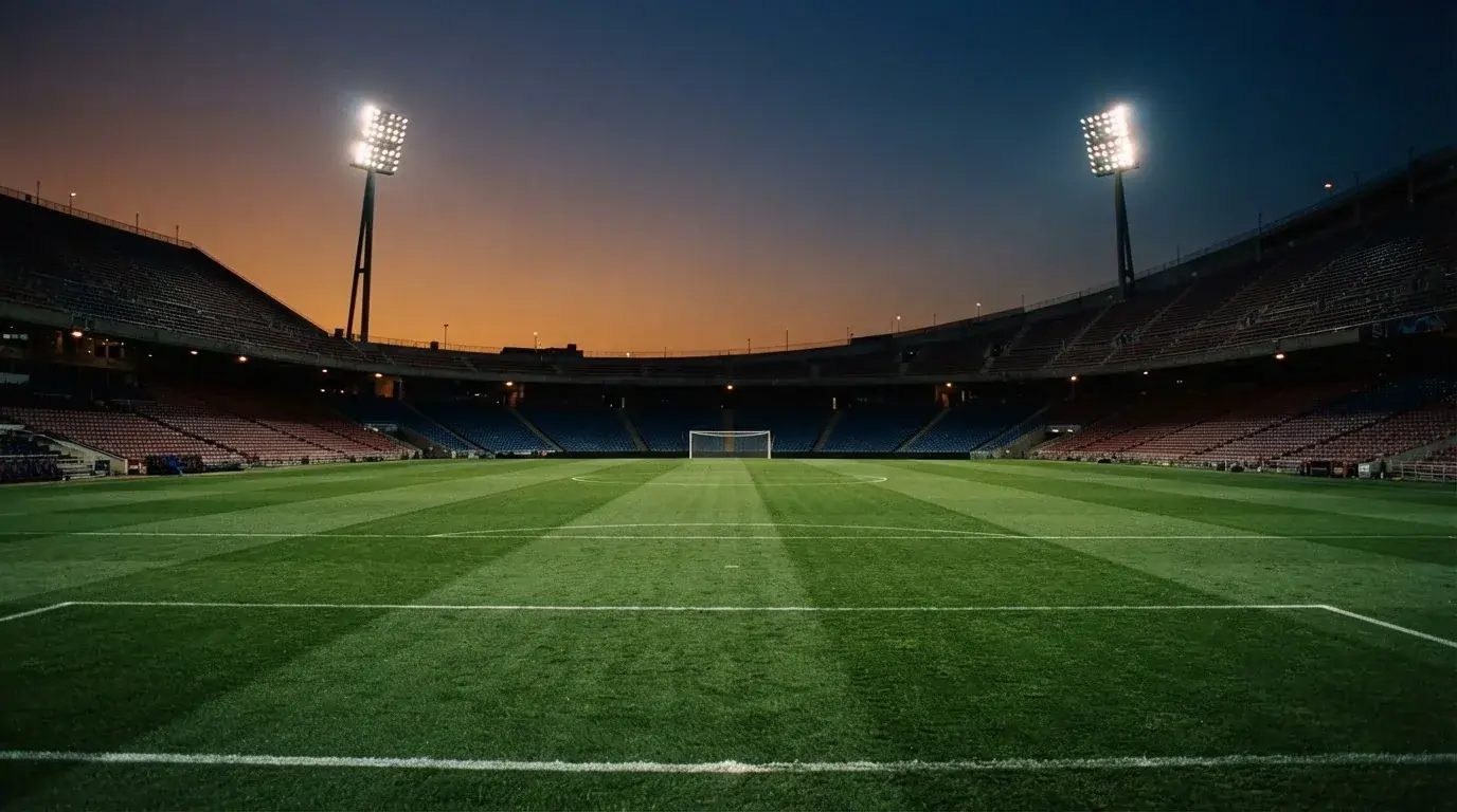 Een leeg voetbalstadion met lichtmasten bij schemering