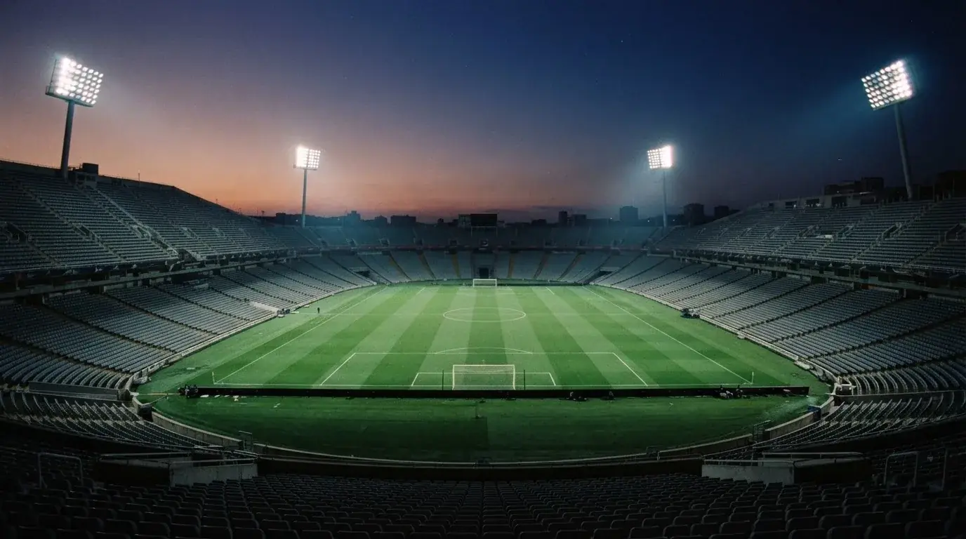 Een leeg voetbalstadion met lichtmasten bij schemering