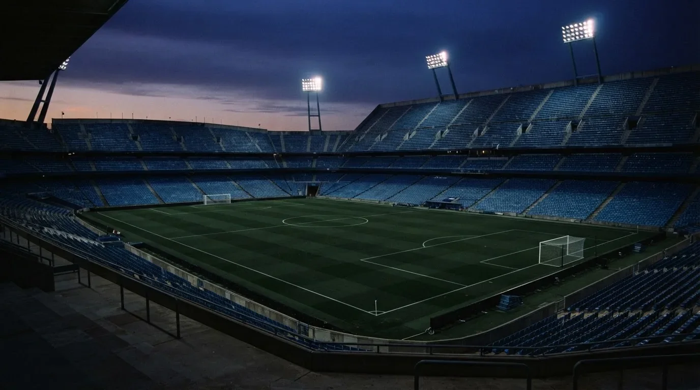 Een leeg voetbalstadion met lichtmasten bij schemering