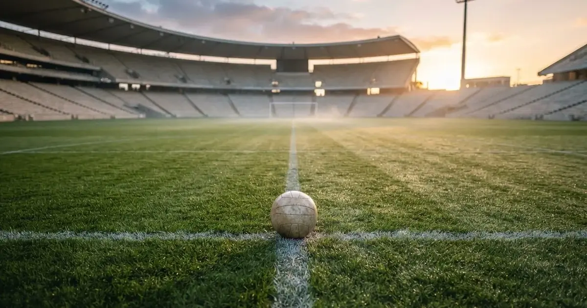 Een voetbal op de middenstip van een grasveld in het ochtendlicht